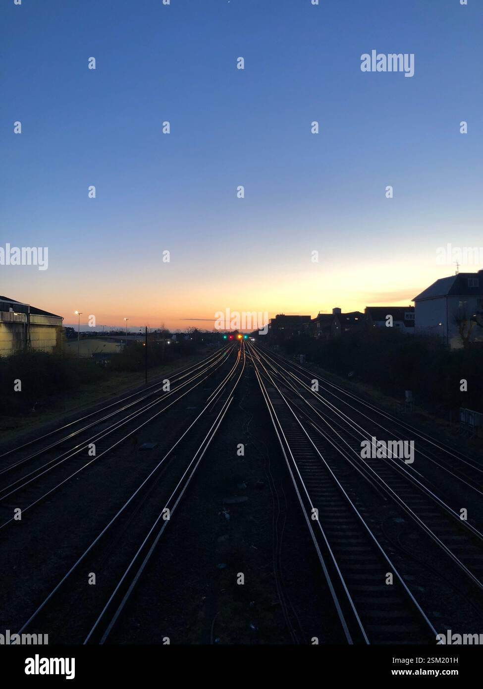 A view of the train tracks going into Wimbledon train station, from the bridge above. Taken at sunset, with the light reflecting off the tracks. - Smartphone Captured Stock Image
