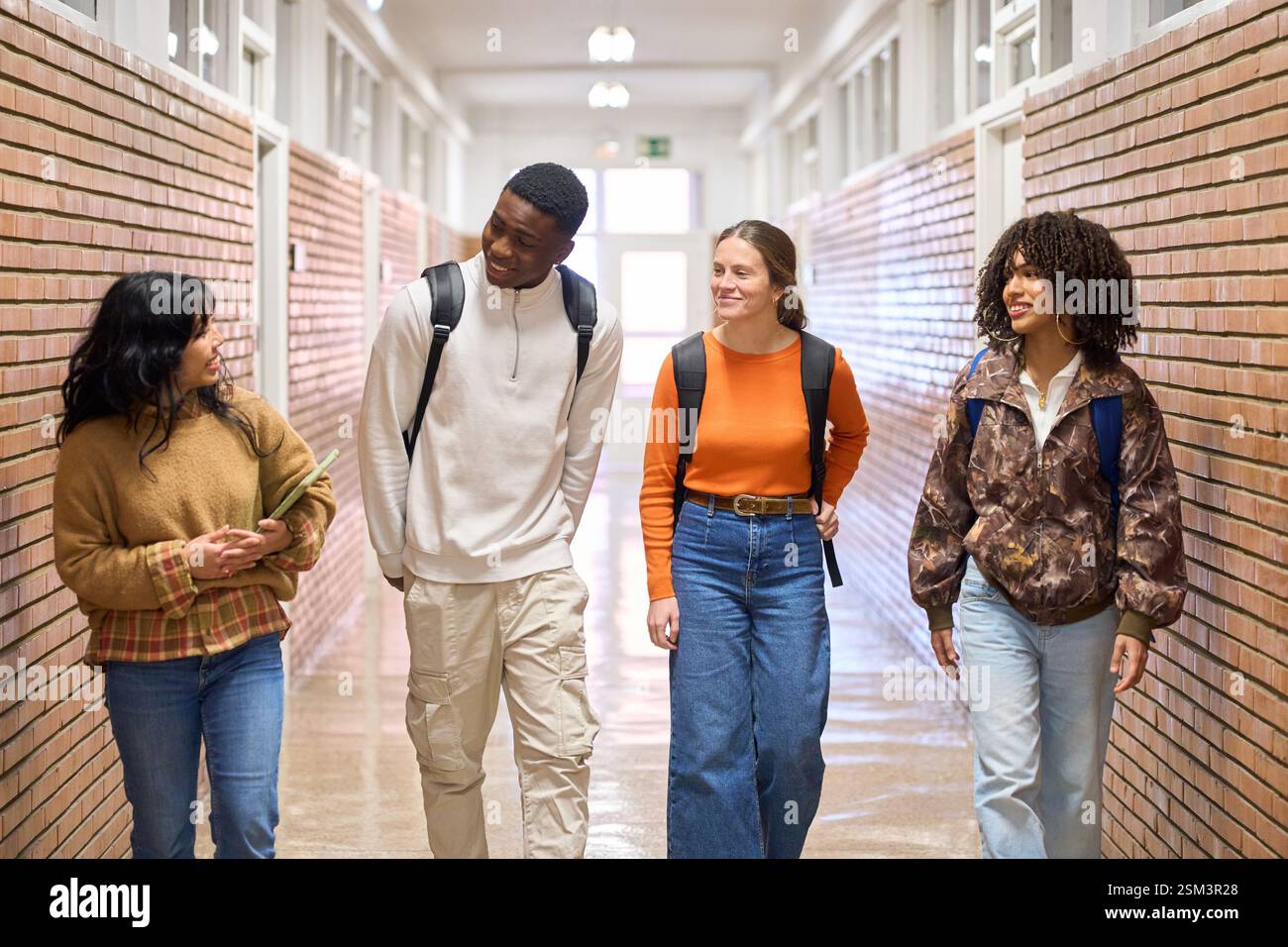 Happy students walking and talking in university corridor Stock Photo