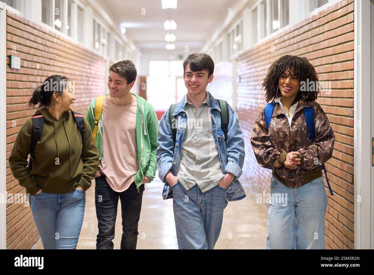 Happy students walking and talking in university hallway Stock Photo