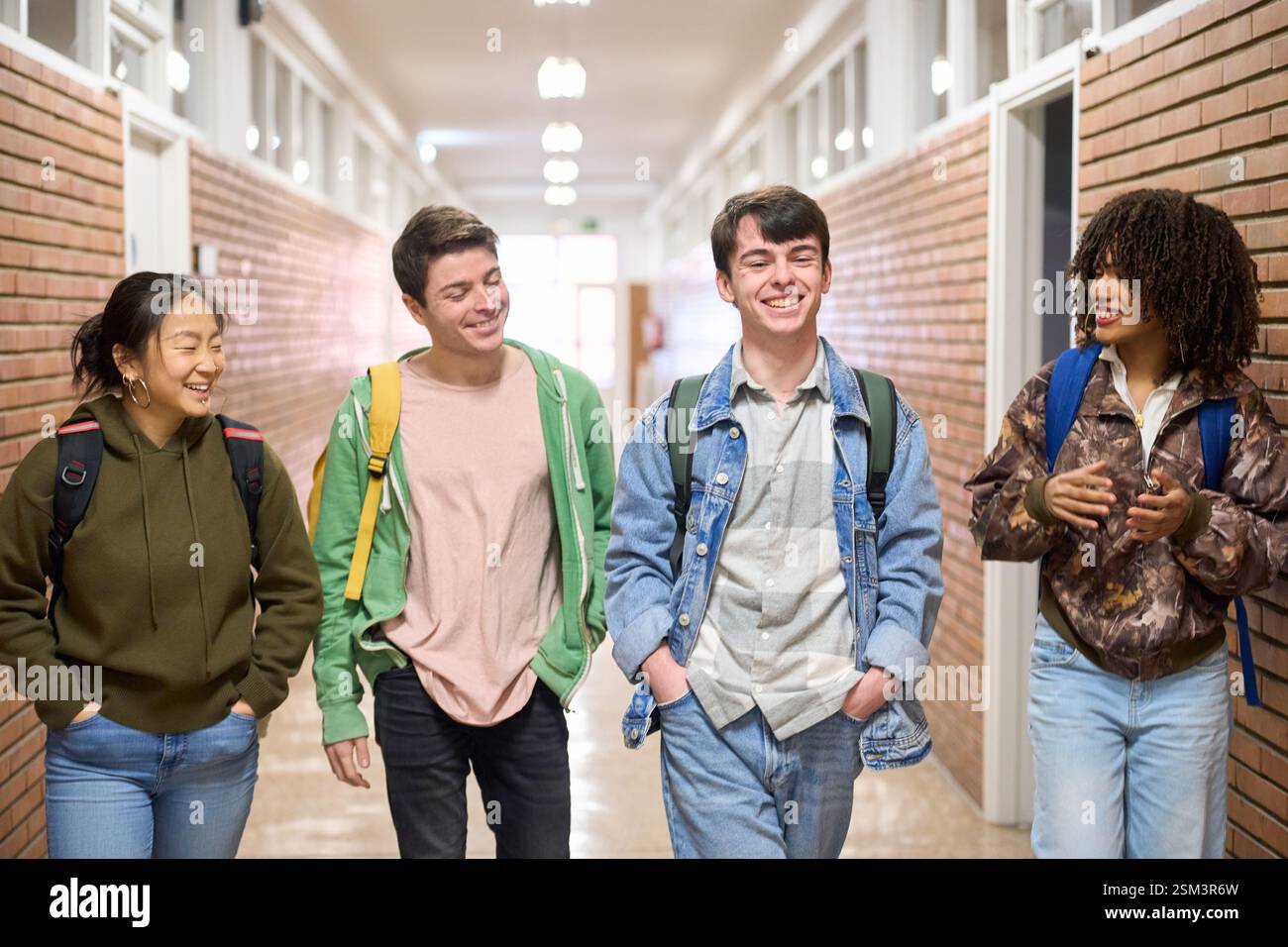 Happy students walking and talking in university hallway Stock Photo