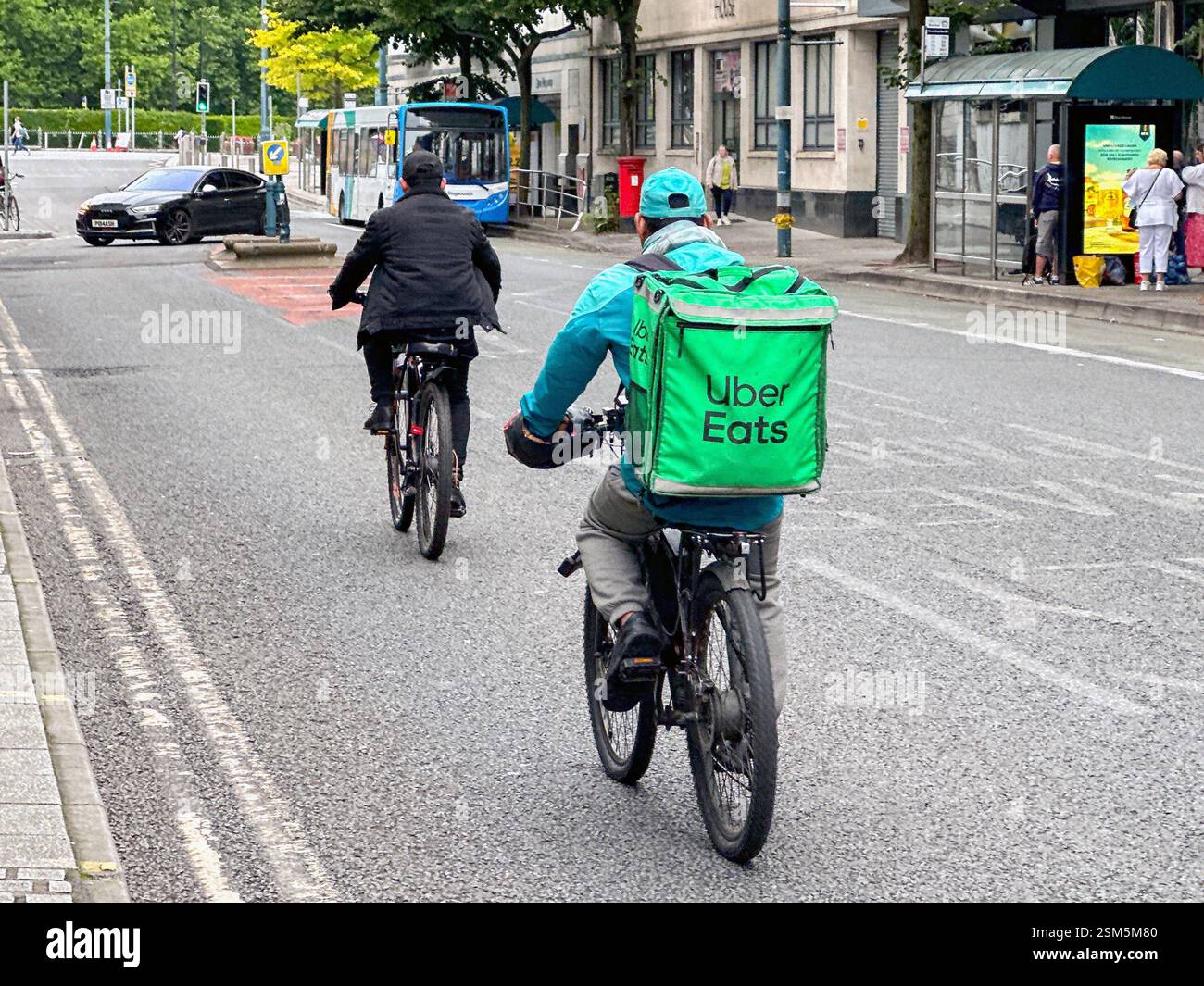 Cardiff, Wales - 24 July 2024: Cyclist on a street in Cardiff city centre delivering takeaway food for Uber Eats Stock Photo