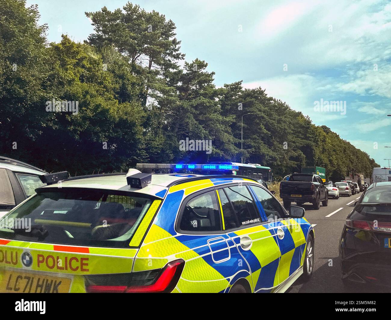 Cardiff, Wales, UK - 31 July 2024: Police car with blue lights flashing driving through queuing traffic on the A4232 dual carriageway into Cardiff - Smartphone Captured Stock Image