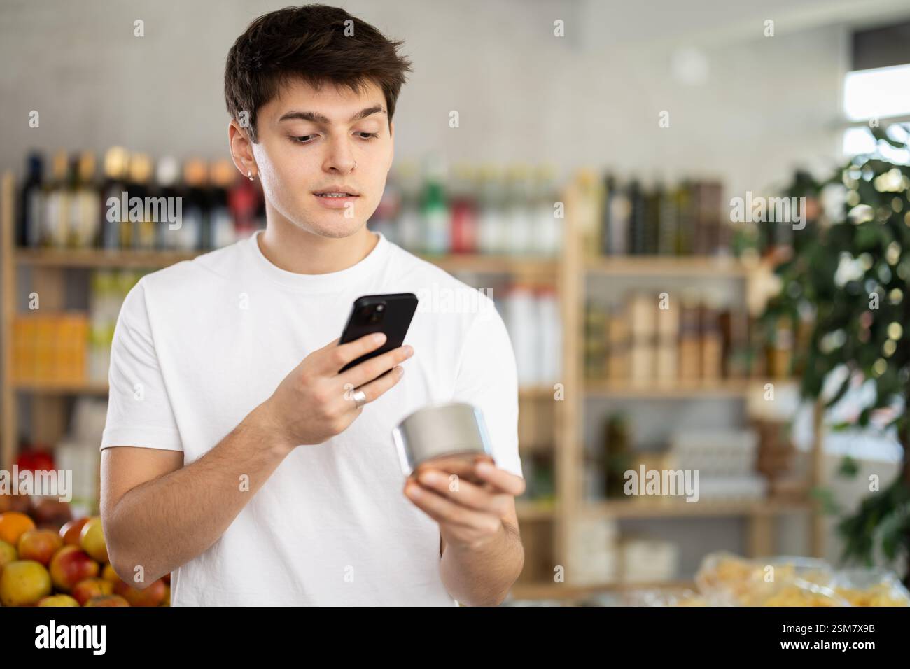 Guy shopper scanning QR code on tin can label in grocery department of ...