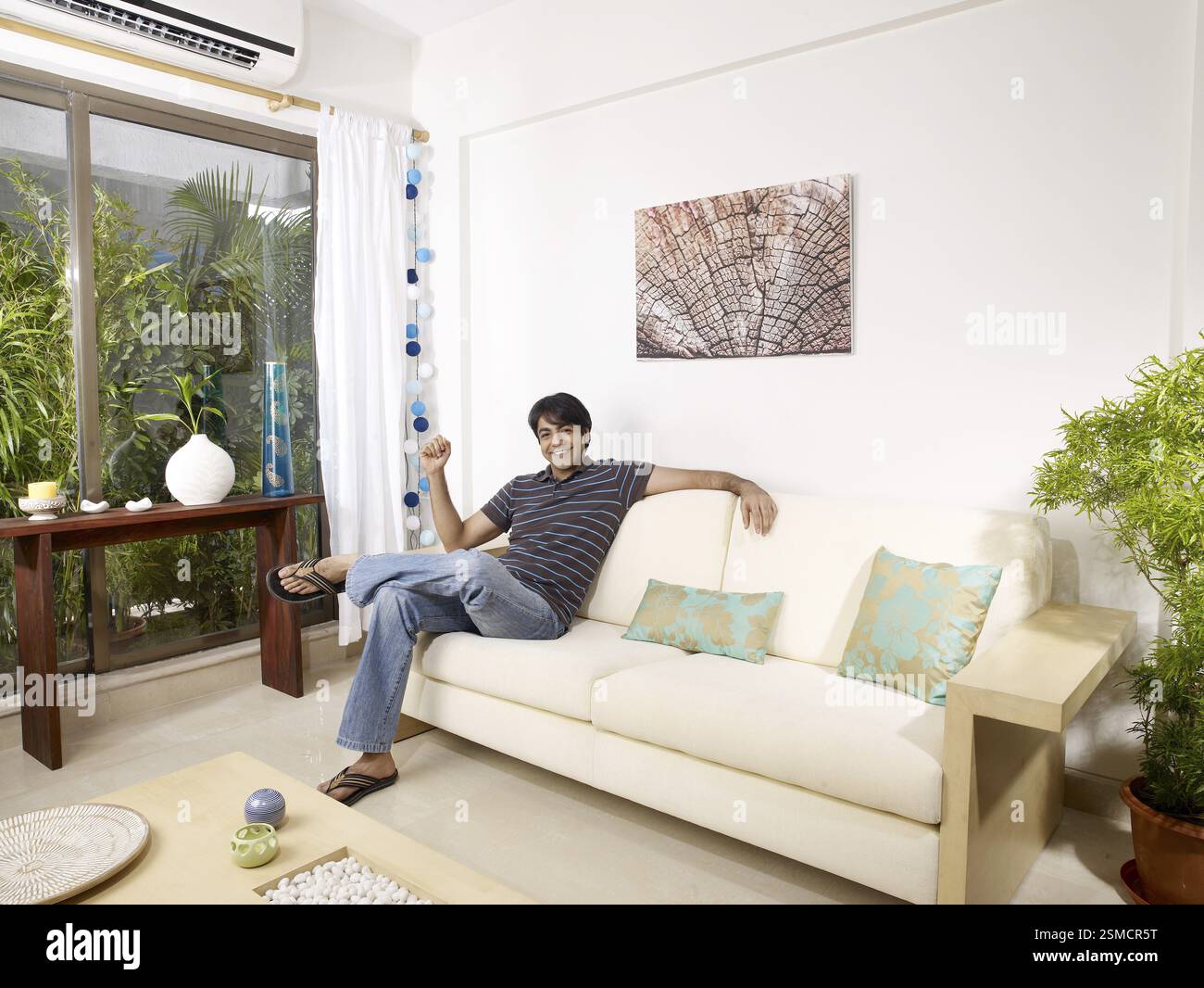 Young man sitting on sofa MR#702V Stock Photo