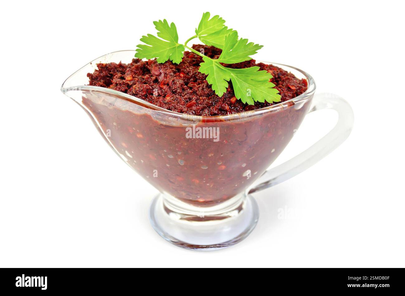 Tabasco adjika in a glass gravy boat with a sprig of parsley isolated on white background Stock Photo