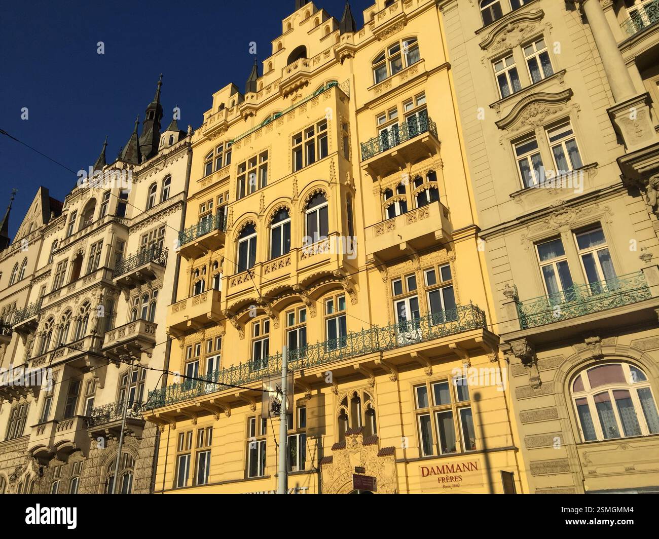 Facade of ornate yellow building with wrought iron balconies and arched ...