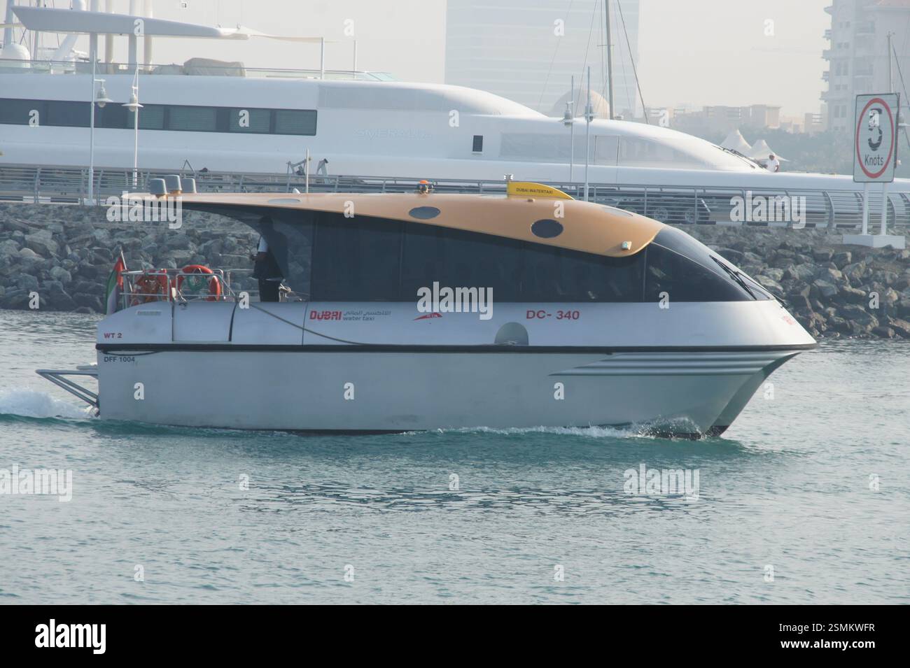 A small RTA Water Taxi bobs in the waves in front of a massive luxury ...