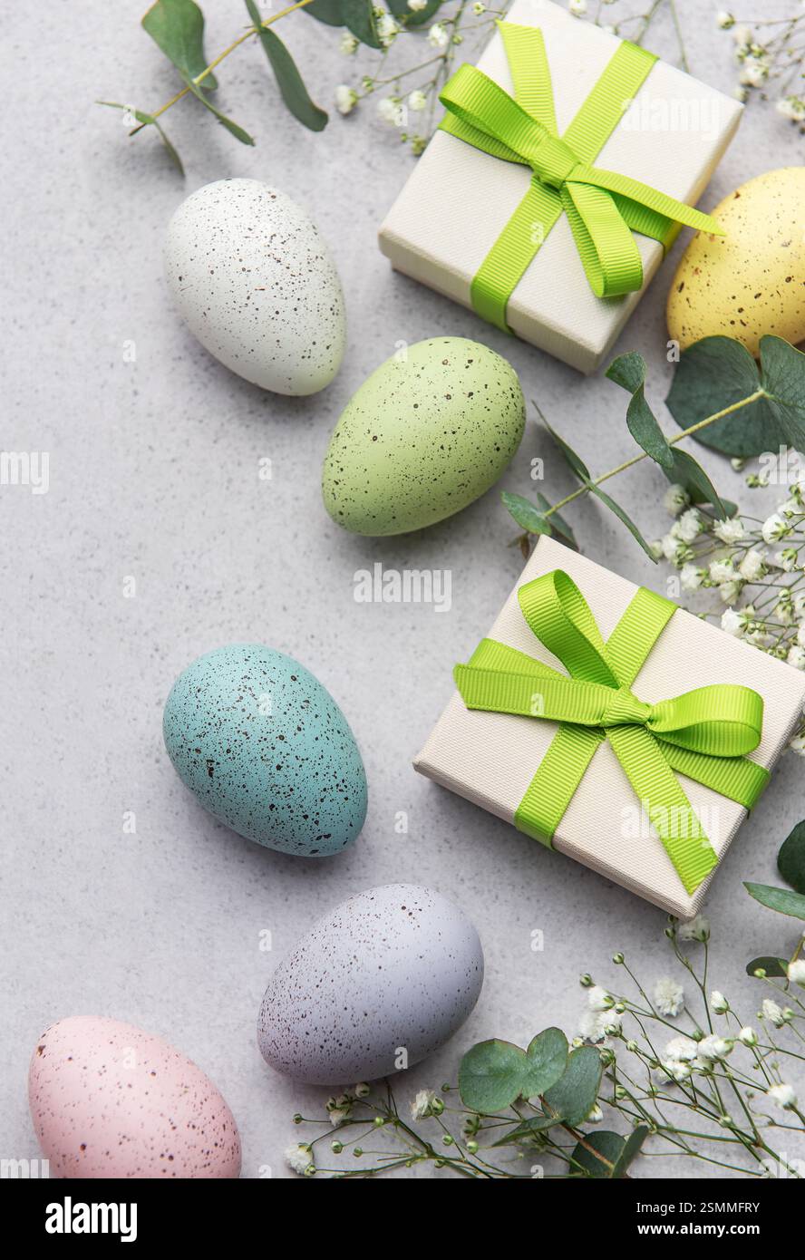 Vibrant easter eggs and gifts on a textured background with eucalyptus leaves Stock Photo