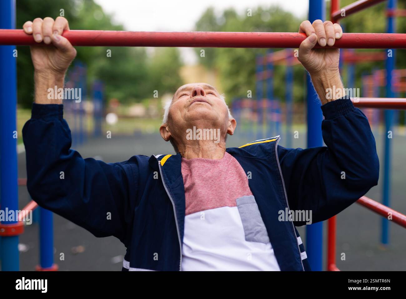 Sportive old man doing pull-ups outdoors Stock Photo