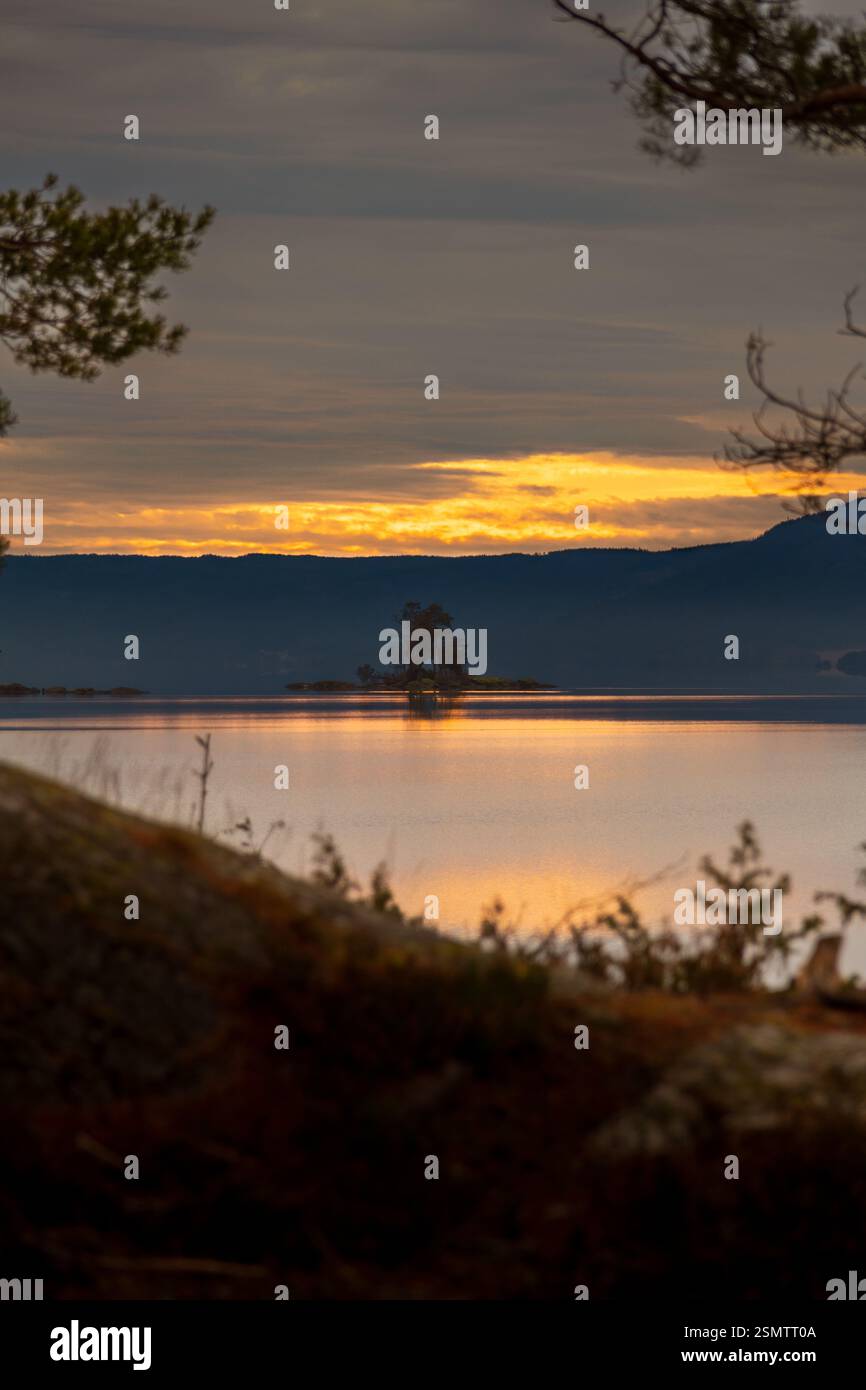 Randsfjorden at sunset, where sky and earth become one. Still waters reflect the golden hues of autumn, a dreamy moment frozen in time. Stock Photo