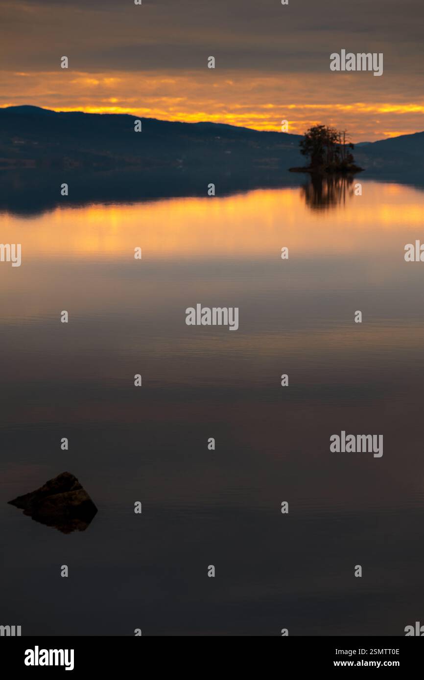 Randsfjorden at sunset, where sky and earth become one. Still waters reflect the golden hues of autumn, a dreamy moment frozen in time. Stock Photo