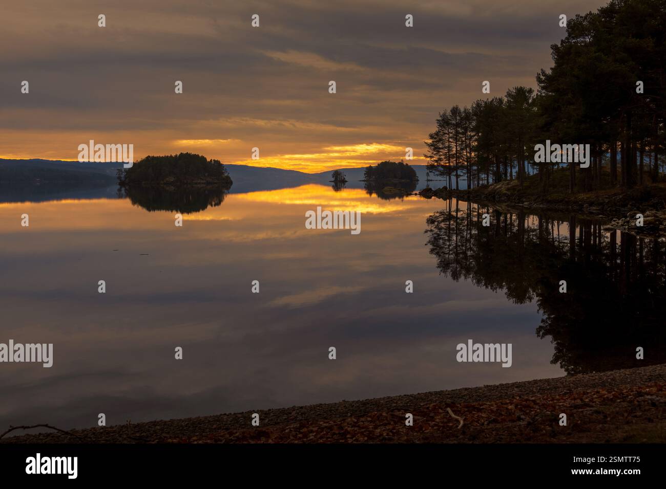 Randsfjorden at sunset, where sky and earth become one. Still waters reflect the golden hues of autumn, a dreamy moment frozen in time. Stock Photo