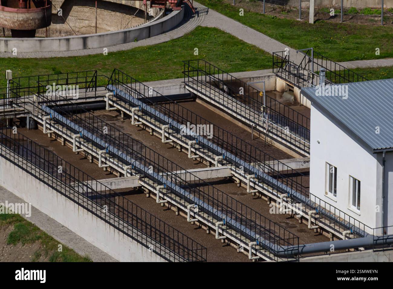 This water treatment facility features several filtration units arranged in rows, situated in a rural setting. Green grass surrounds the concrete stru Stock Photo