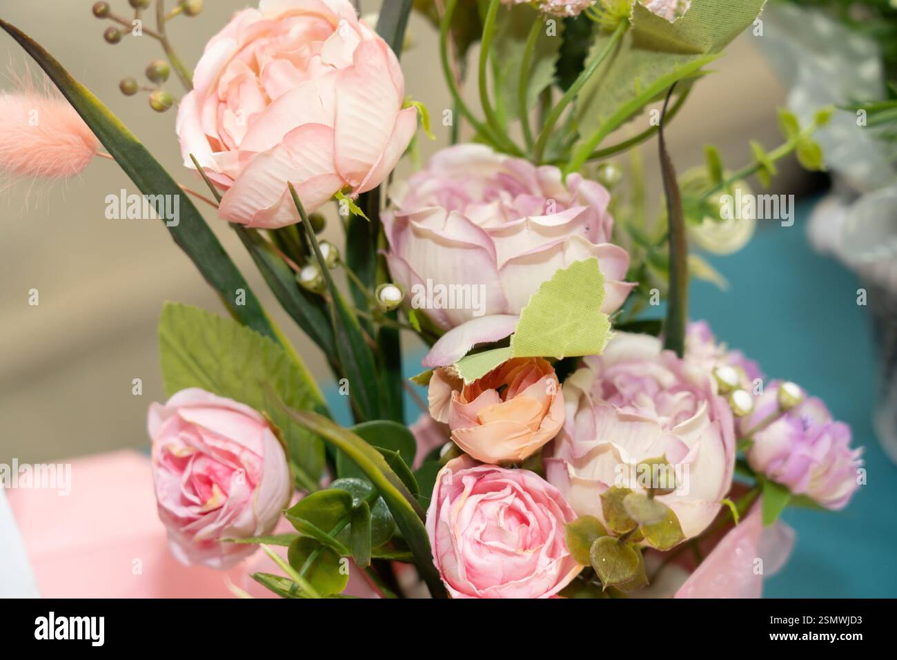 A stunning display of soft pink roses and delicate blooms creates a beautiful floral centerpiece at a spring event. Green leaves and decorative elemen Stock Photo
