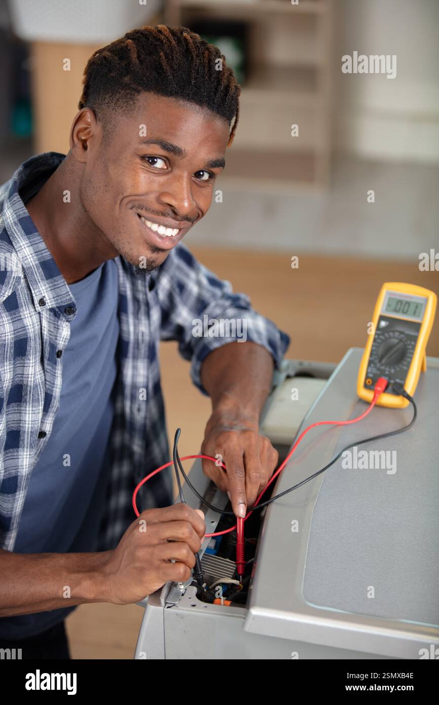 male service-agent testing washing machine with a multimeter Stock Photo