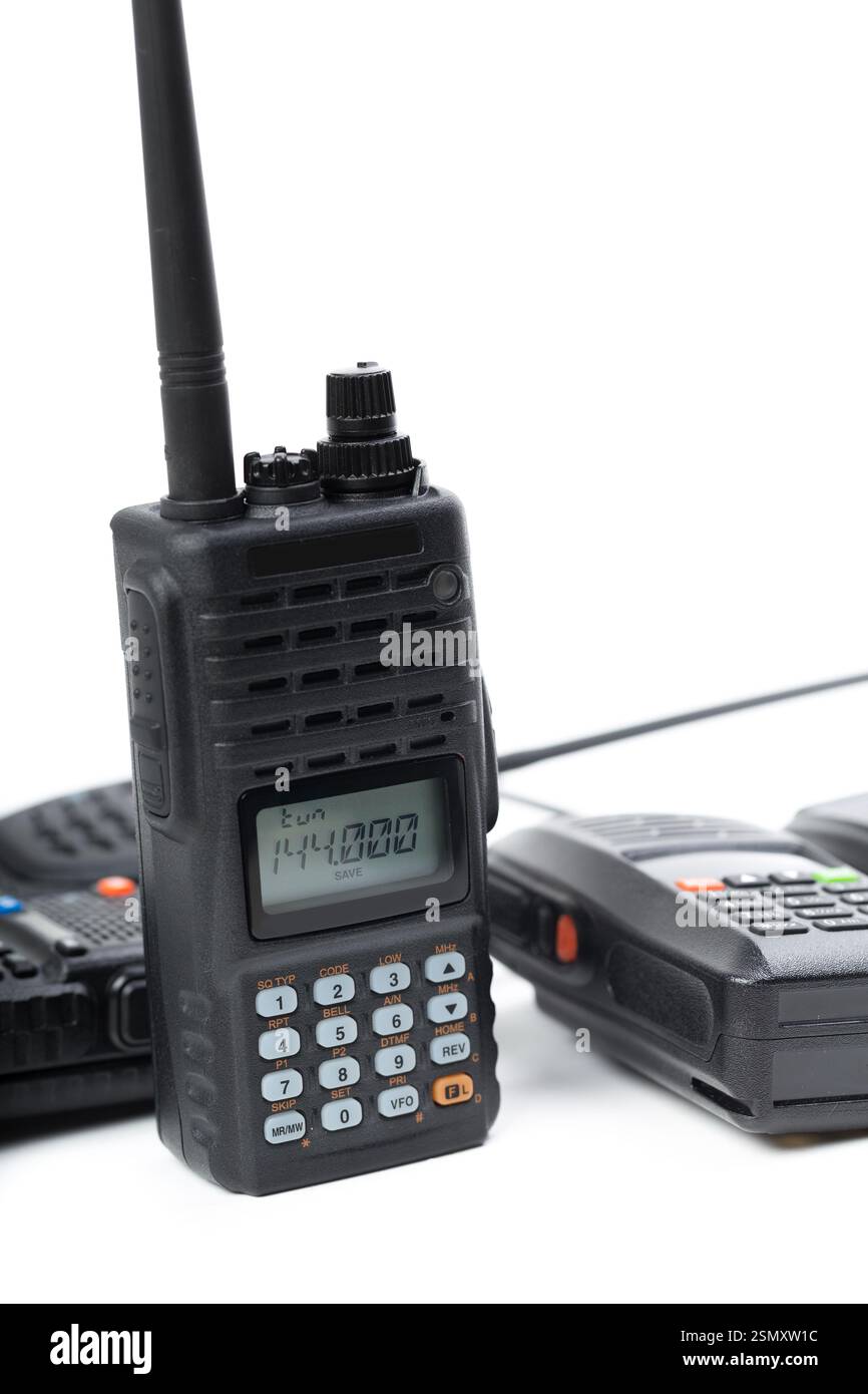 Handheld radios arranged on a white surface showing frequency display ...