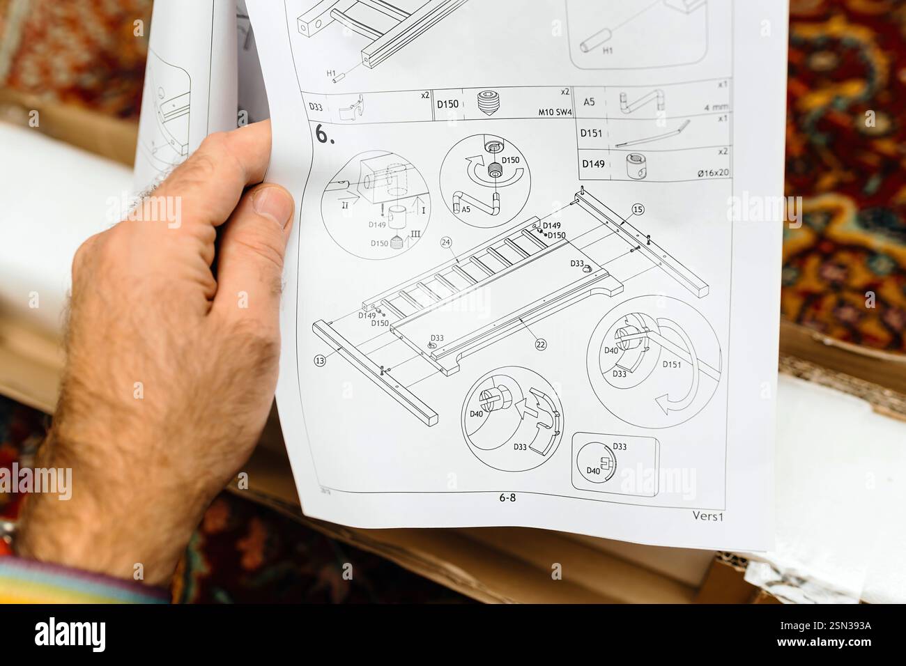 A close-up of a hand holding an instruction manual with technical ...