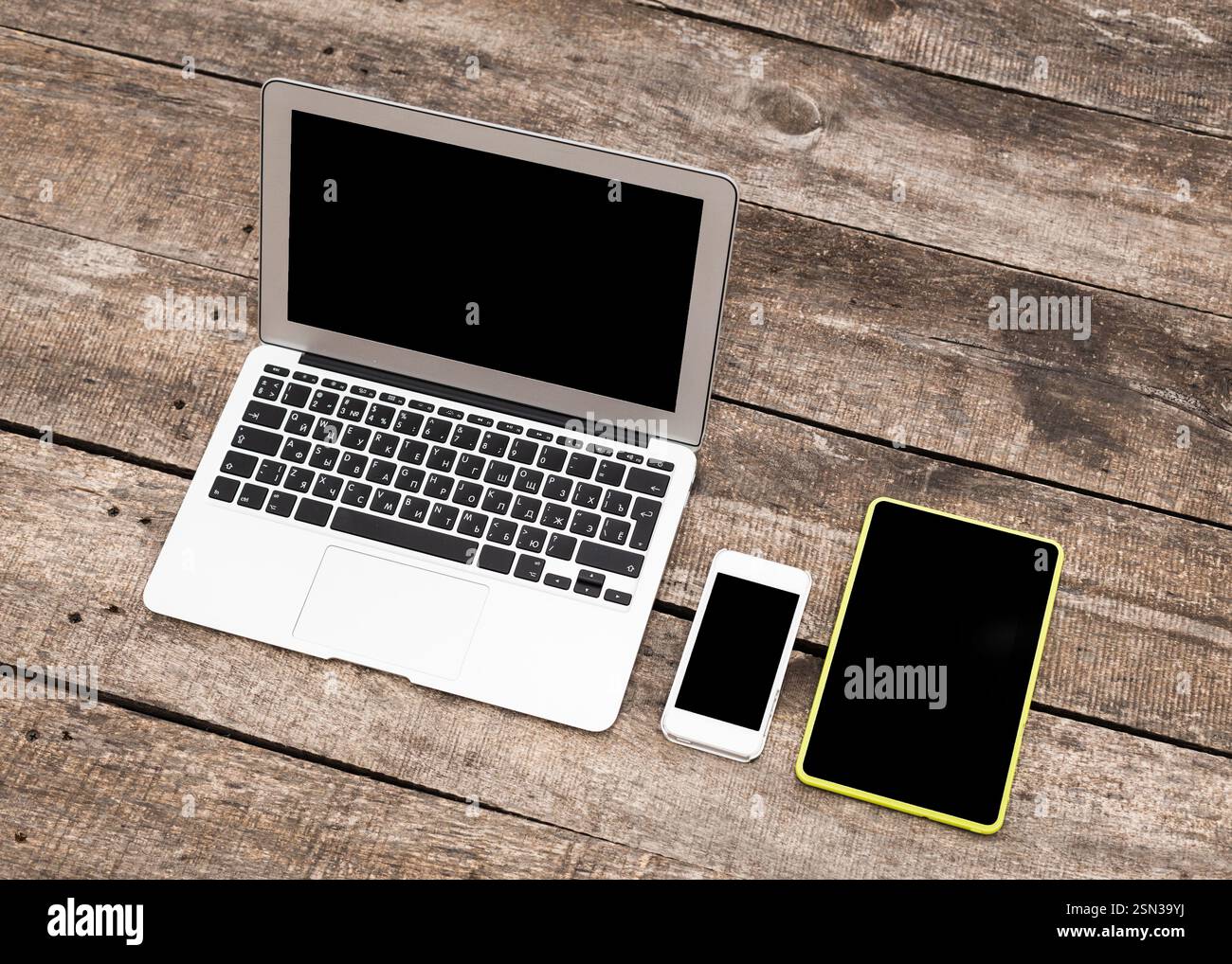 Various electronic devices arranged on a rustic wooden table during daylight Stock Photo