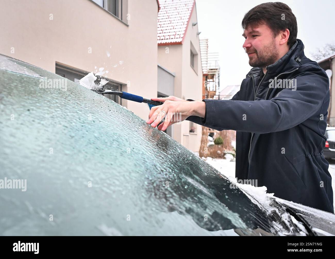 Driver scraping ice from the car window in Trest, Czech Republic
