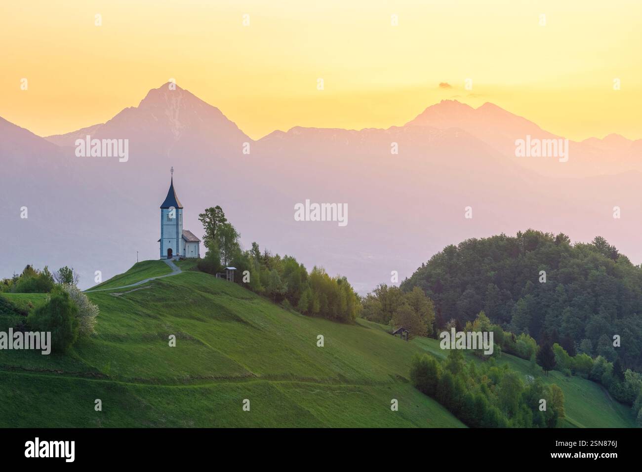 View of the iconic Jamnik church, with Mount Triglav on the background, at sunrise. Jamnik, Kranj, Upper Carniola, Slovenia. Stock Photo