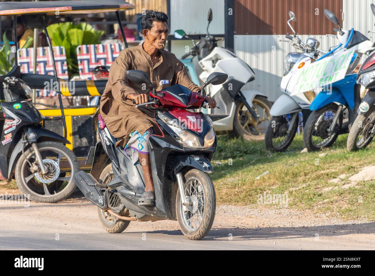 KOH LANTA, THAILAND, DEC 02 2024, Smoking man riding a motorcycle Stock Photo