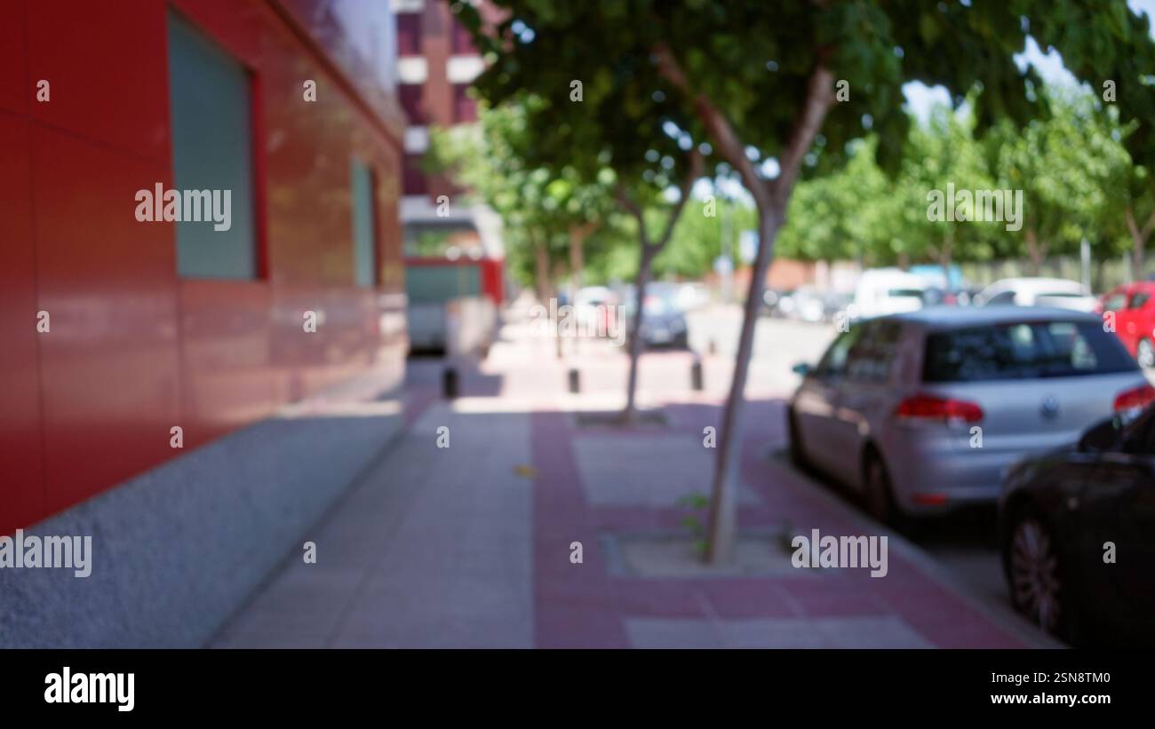 Blurred urban street scene with defocused cars parked on both sides ...