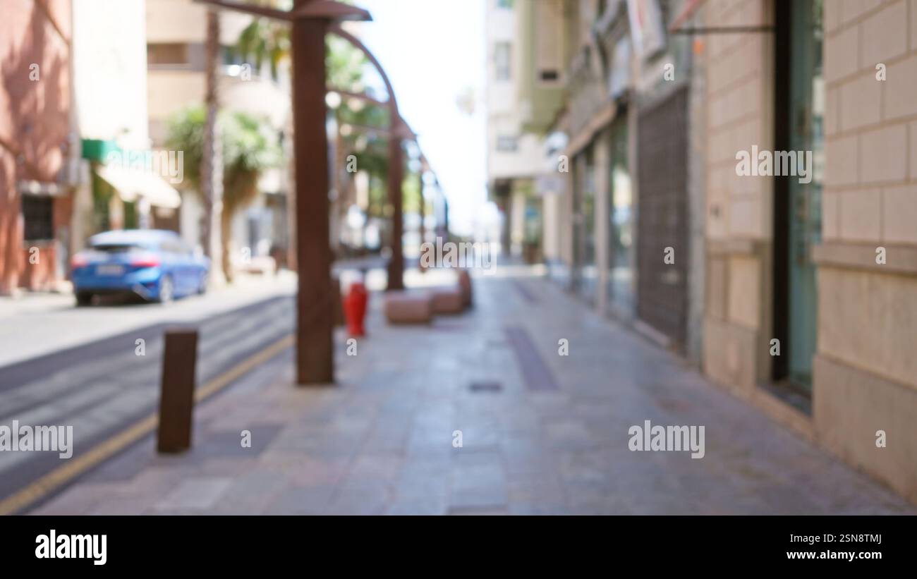 Blurred city street scene with defocused buildings and cars under ...