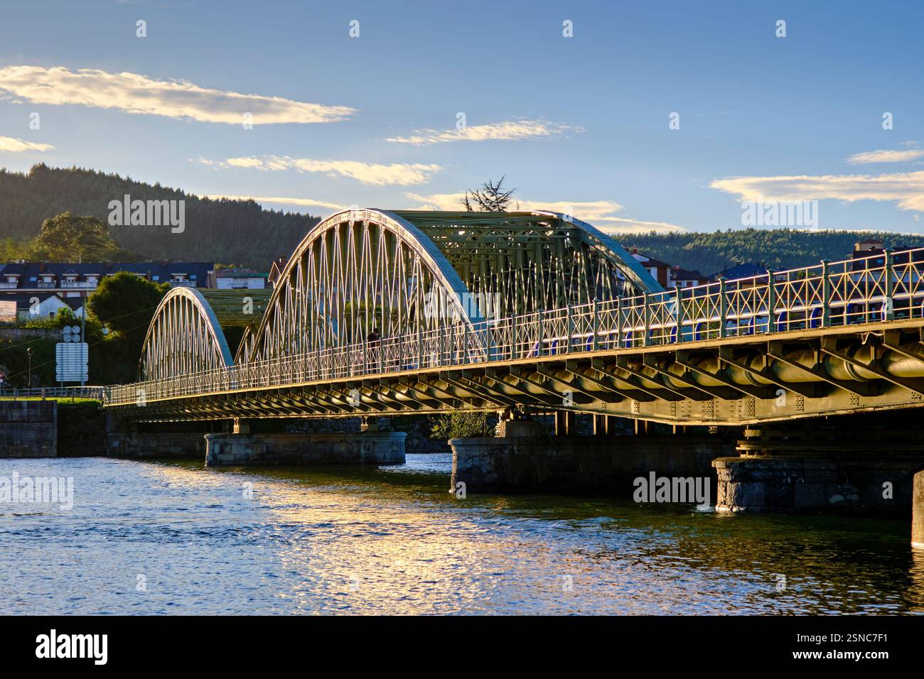 Elegant arch bridge crossing a serene river under a clear blue sky. Colindres, cantabria, spain Stock Photo