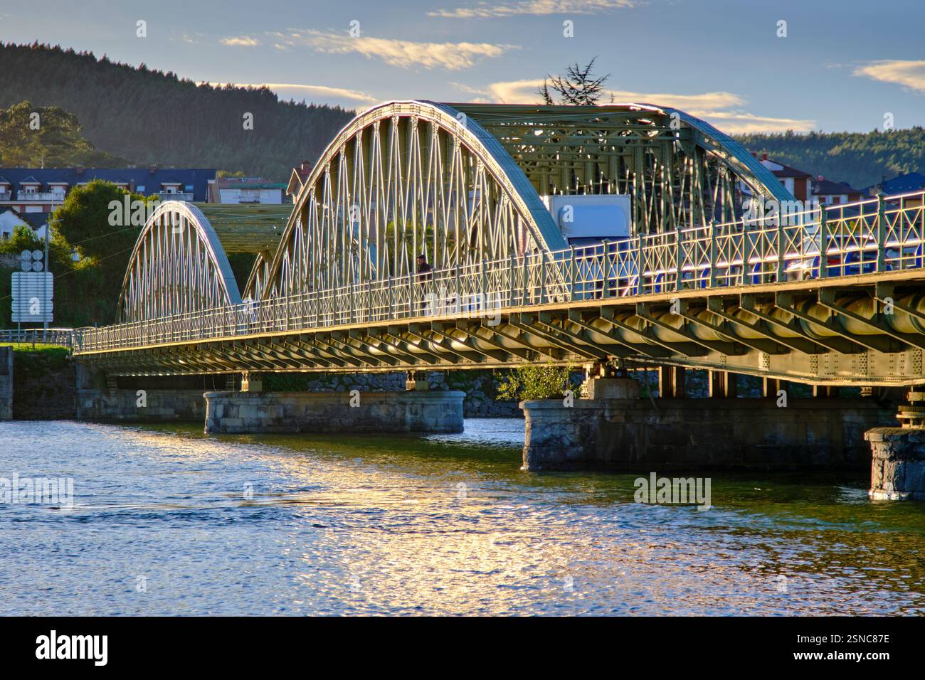 Steel bridge with arches crossing a calm river at sunset. Colindres, cantabria, spain Stock Photo