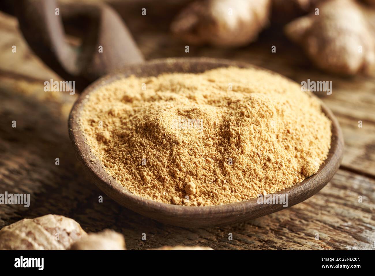 Ground ginger powder on a spoon with fresh root Stock Photo