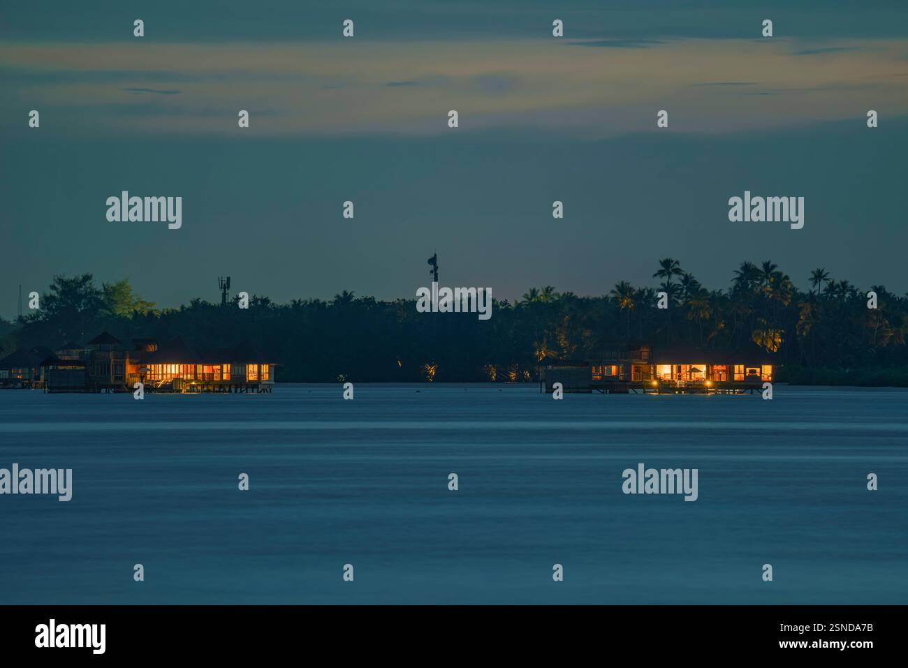 Unique landscape about the Maldives. Illuminated Luxury ocean over villas at blue hour. Stock Photo