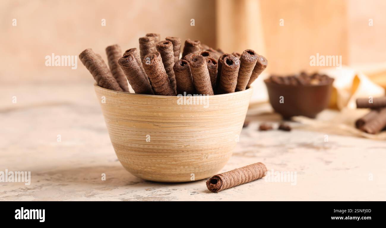 Bowl of delicious chocolate wafer rolls on table Stock Photo