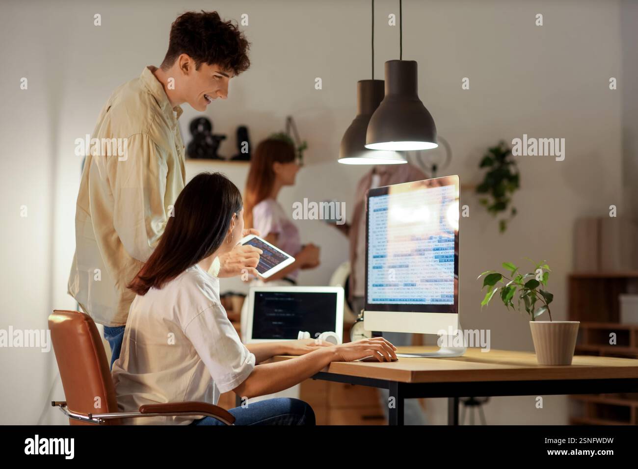 Young programmers working with gadgets in office at night Stock Photo