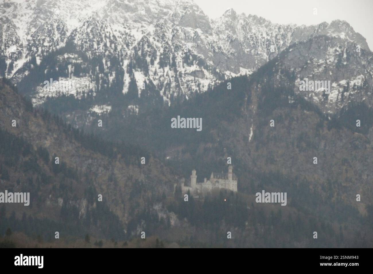 A white castle sits atop a mountain in Germany, Munich, surrounded by ...