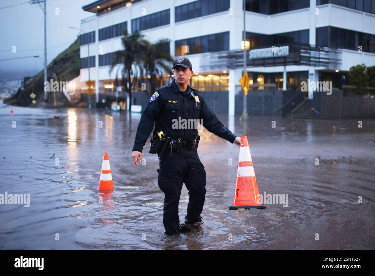 A police officer stands in a flooded intersection during a storm ...