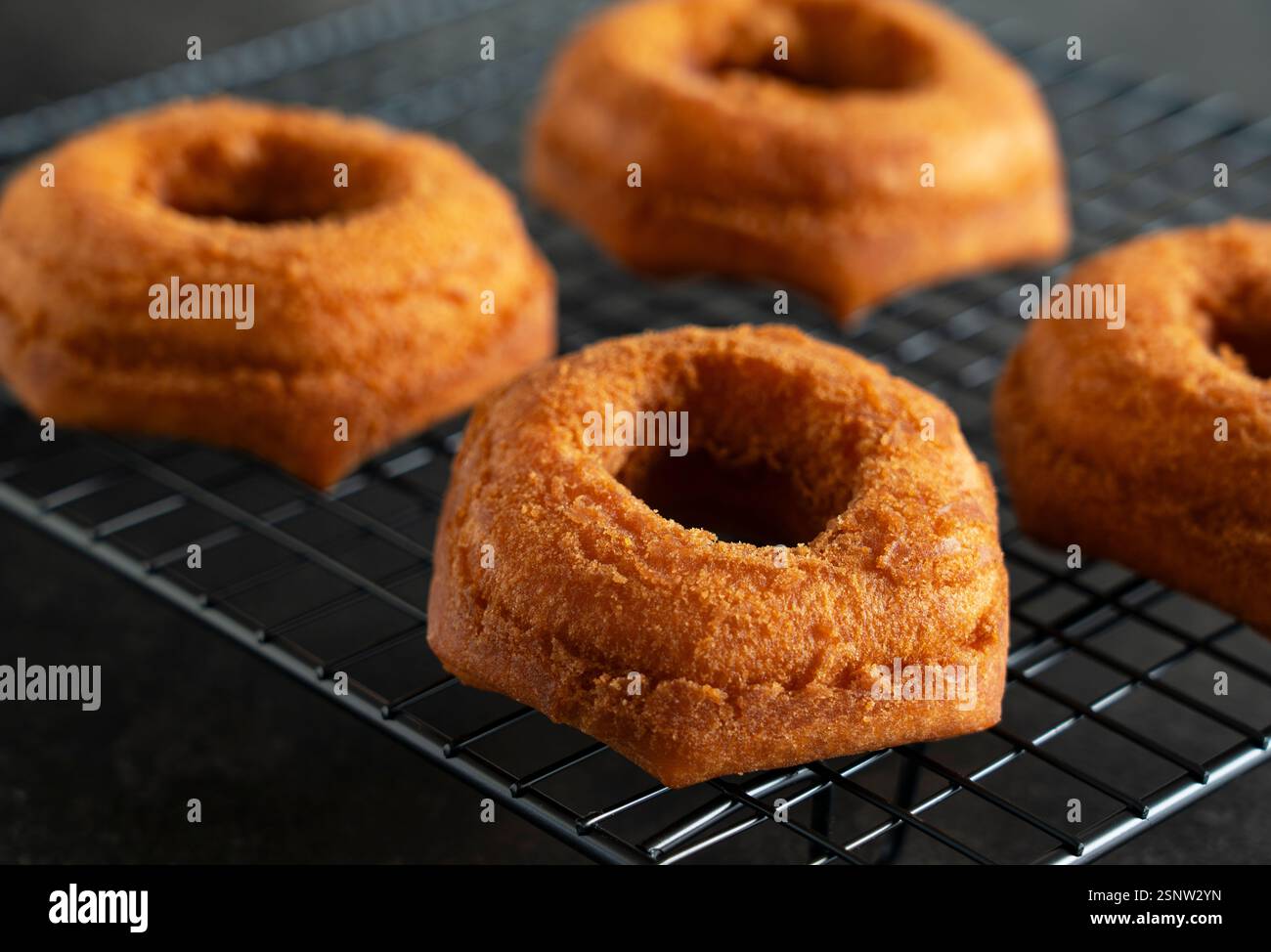 Freshly Placed Donut on a Cooling Rack with Black Background Stock Photo