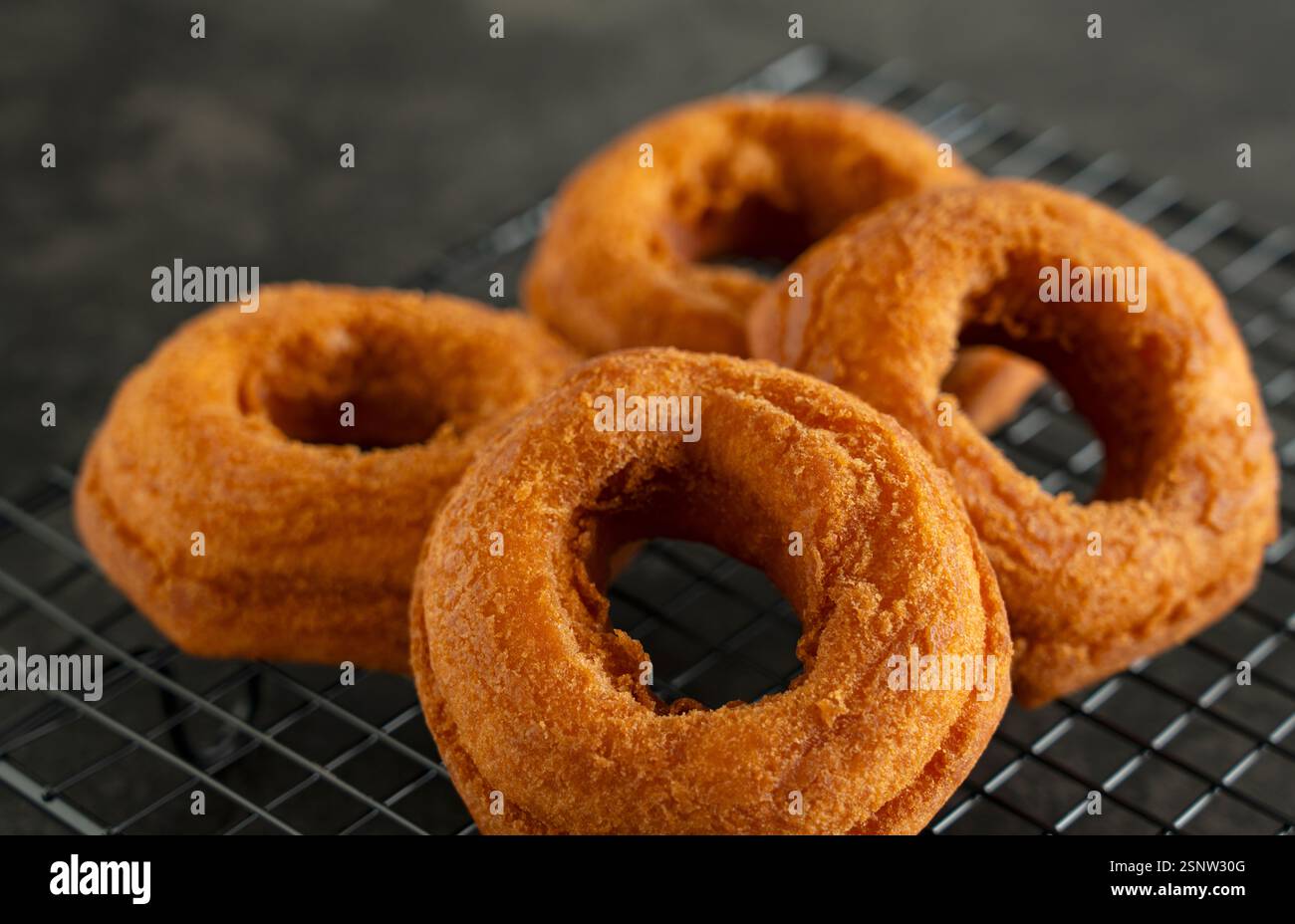Freshly Placed Donut on a Cooling Rack with Black Background Stock Photo
