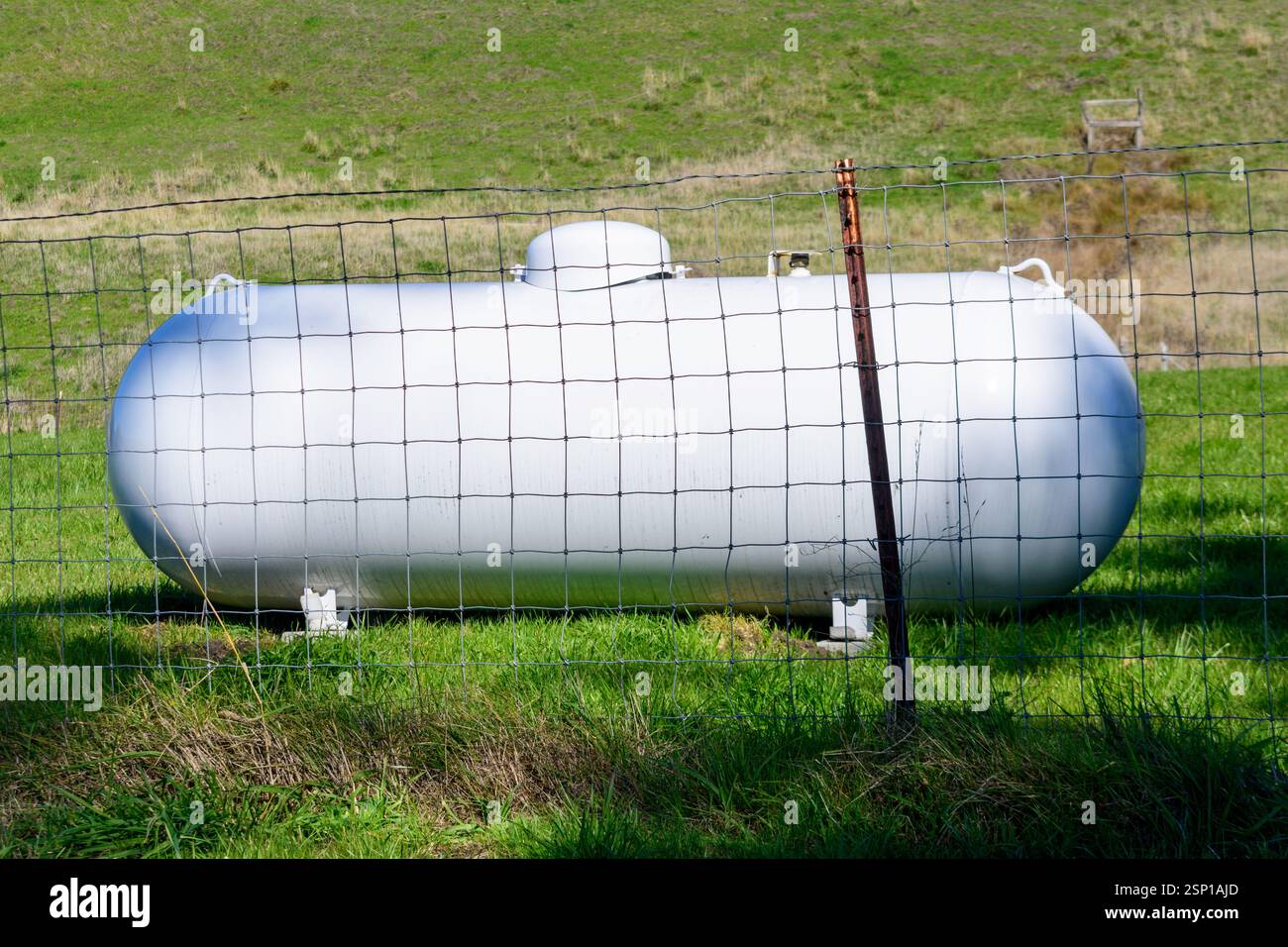 Industrial propane storage tank secured by a metal fence in a rural ...