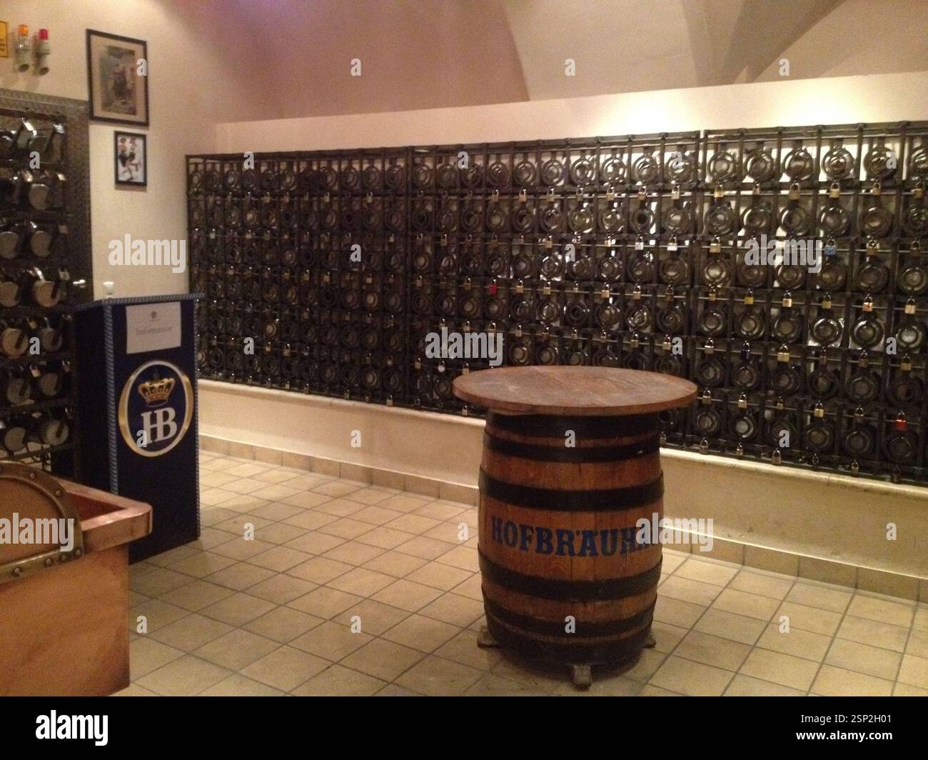 Interior of Hofbräuhaus Munich, featuring a wall of beer steins and a wooden barrel table. Authentic Bavarian atmosphere. The photo also depicts a tra Stock Photo