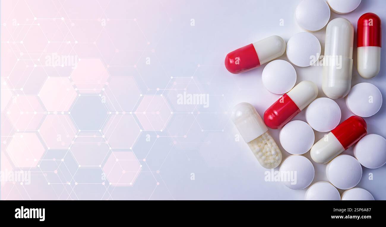 Capsules and tablets in various colors are displayed on a light ...