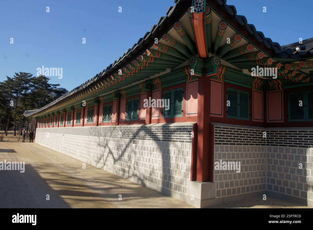 Hamhwadang, Gyeongbokgung Palace. Long corridor with ornate roof and painted eaves. Stone wall with arched windows. Symbol of Korean royal power and a Stock Photo