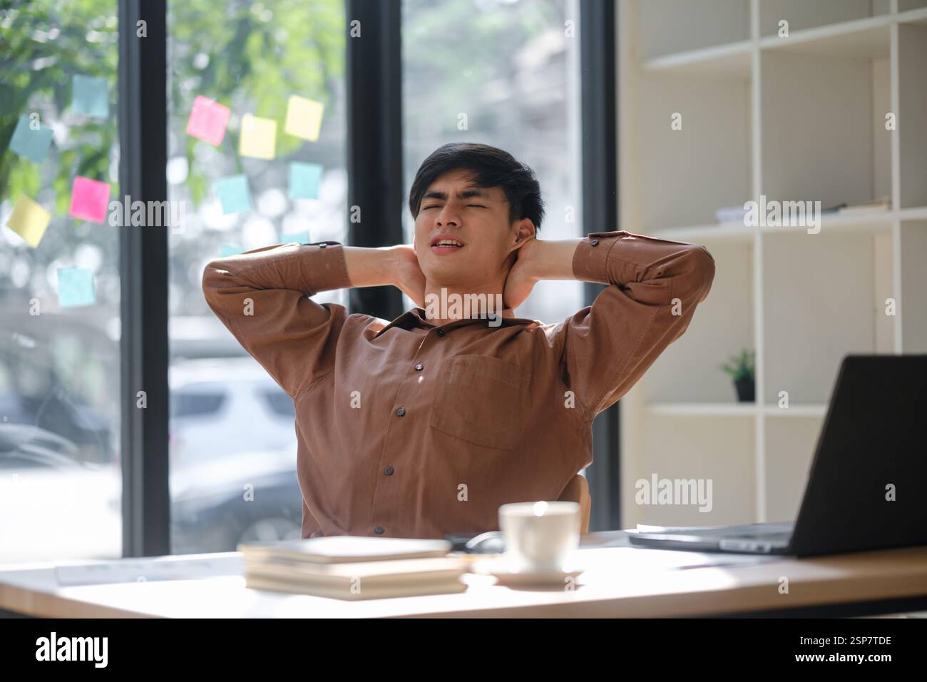 Tired worker experiencing neck and shoulder pain prolonged work hours Stock Photo