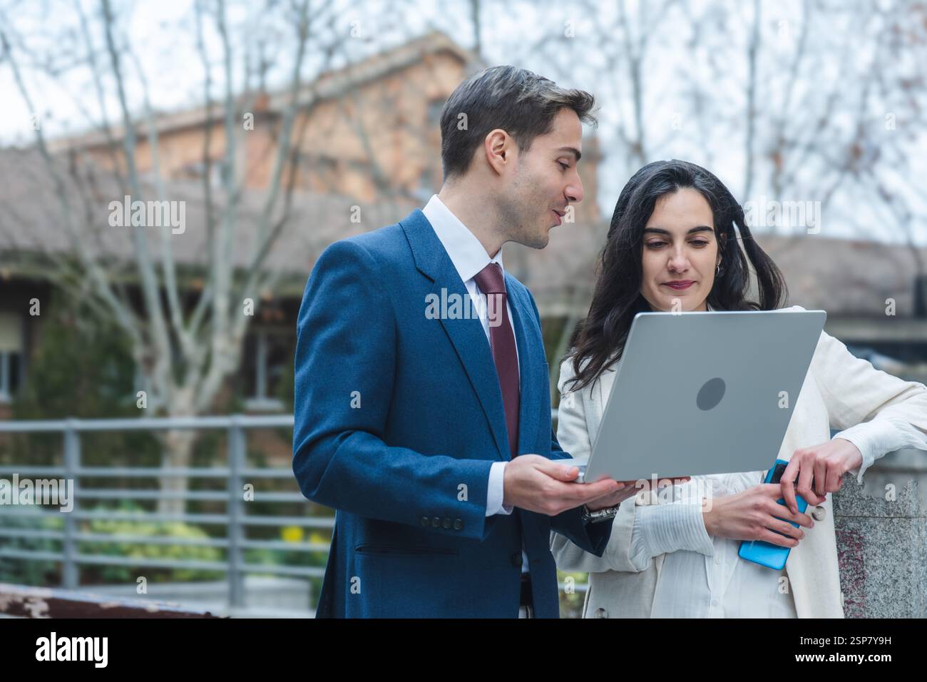 Businessman and businesswoman reviewing information on laptop outdoors Stock Photo