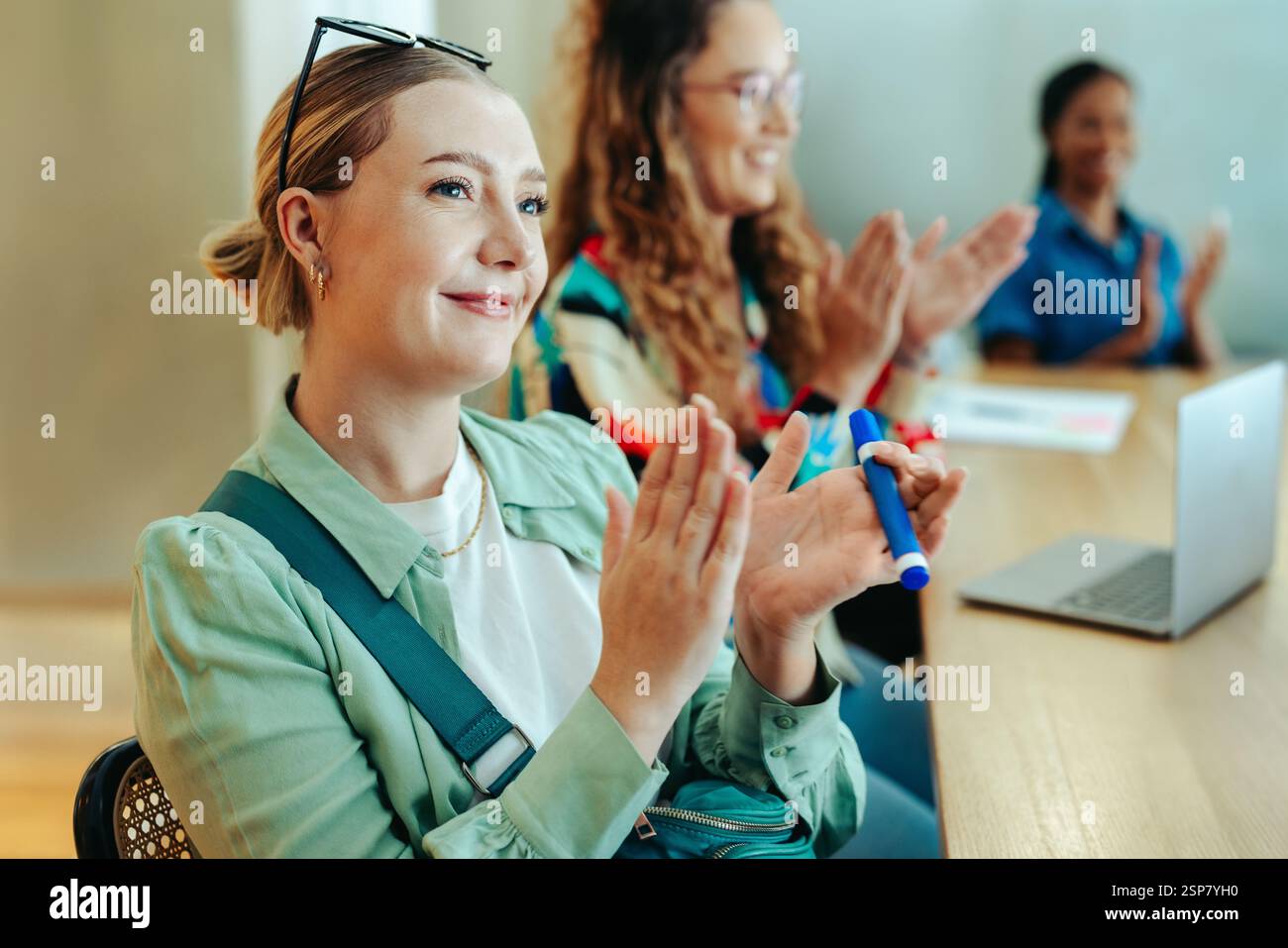 A group of marketing professionals in a casual meeting setting, engaged and applauding. The scene conveys teamwork and appreciation within a modern of Stock Photo
