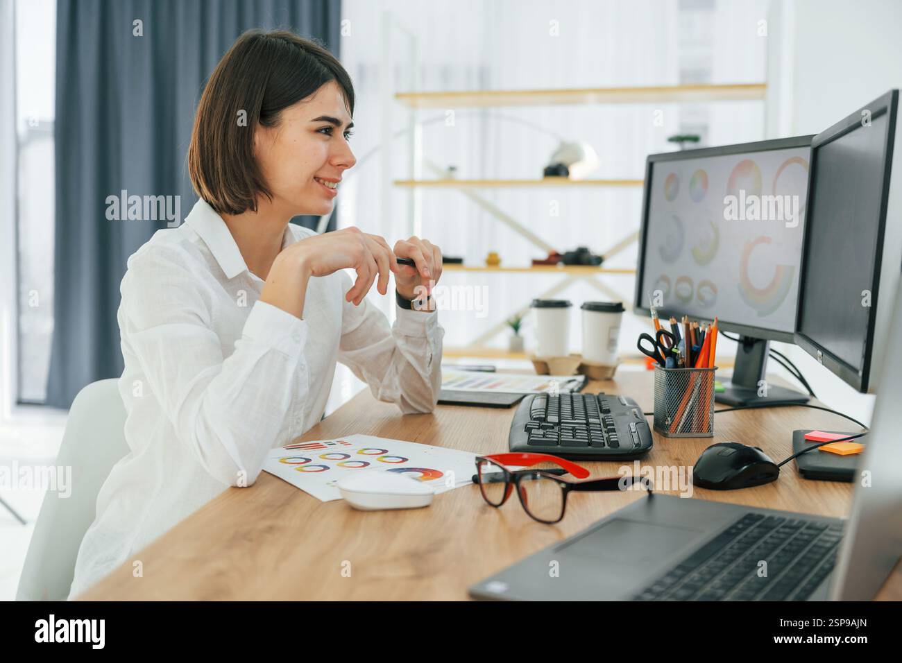 Female designer working in the office by using PC. Stock Photo