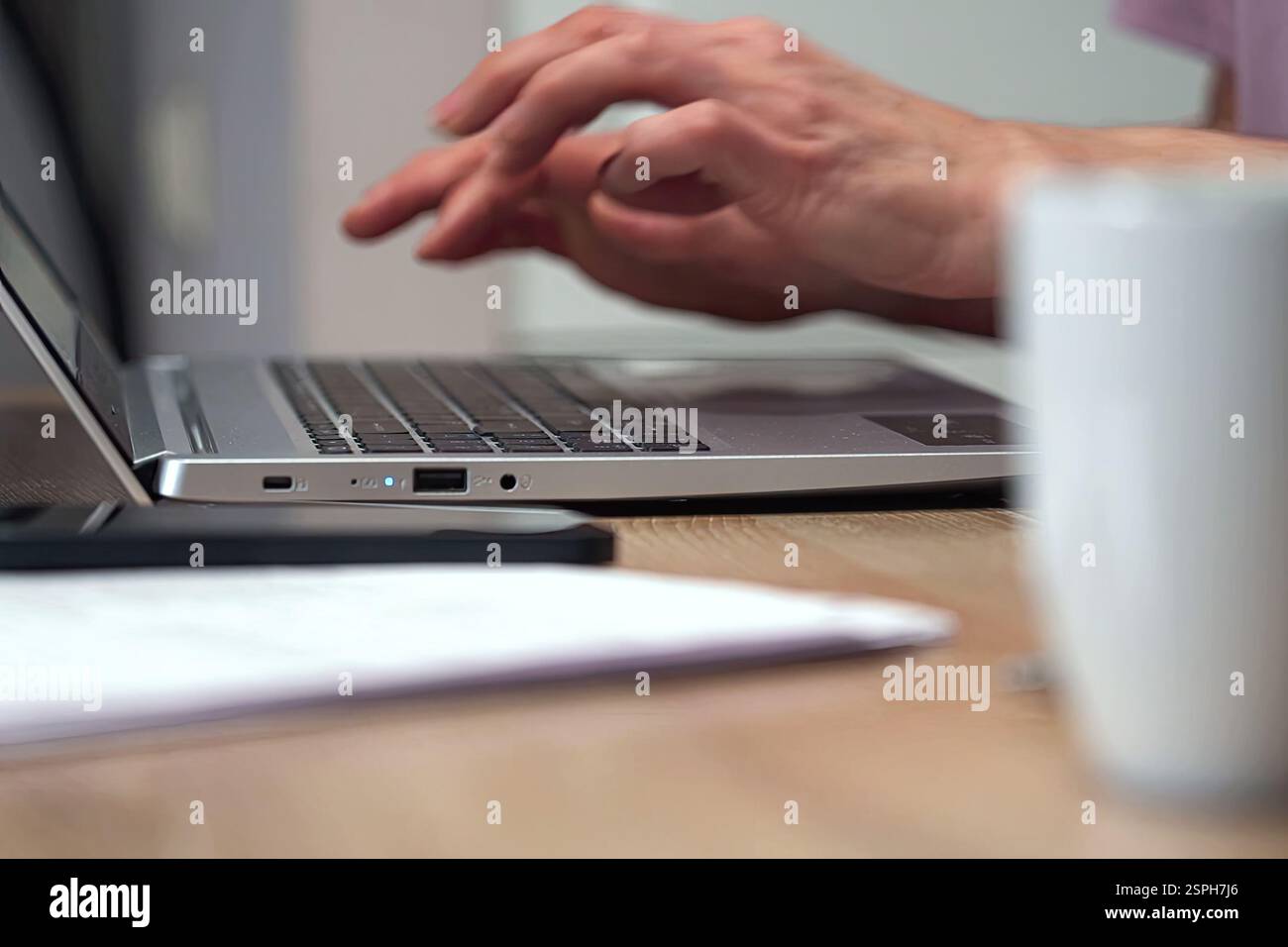 Hands typing on a laptop in a home workspace Stock Photo