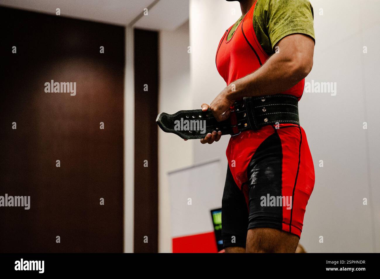 athlete powerlifter tightens weightlifting belt before exercise deadlift Stock Photo