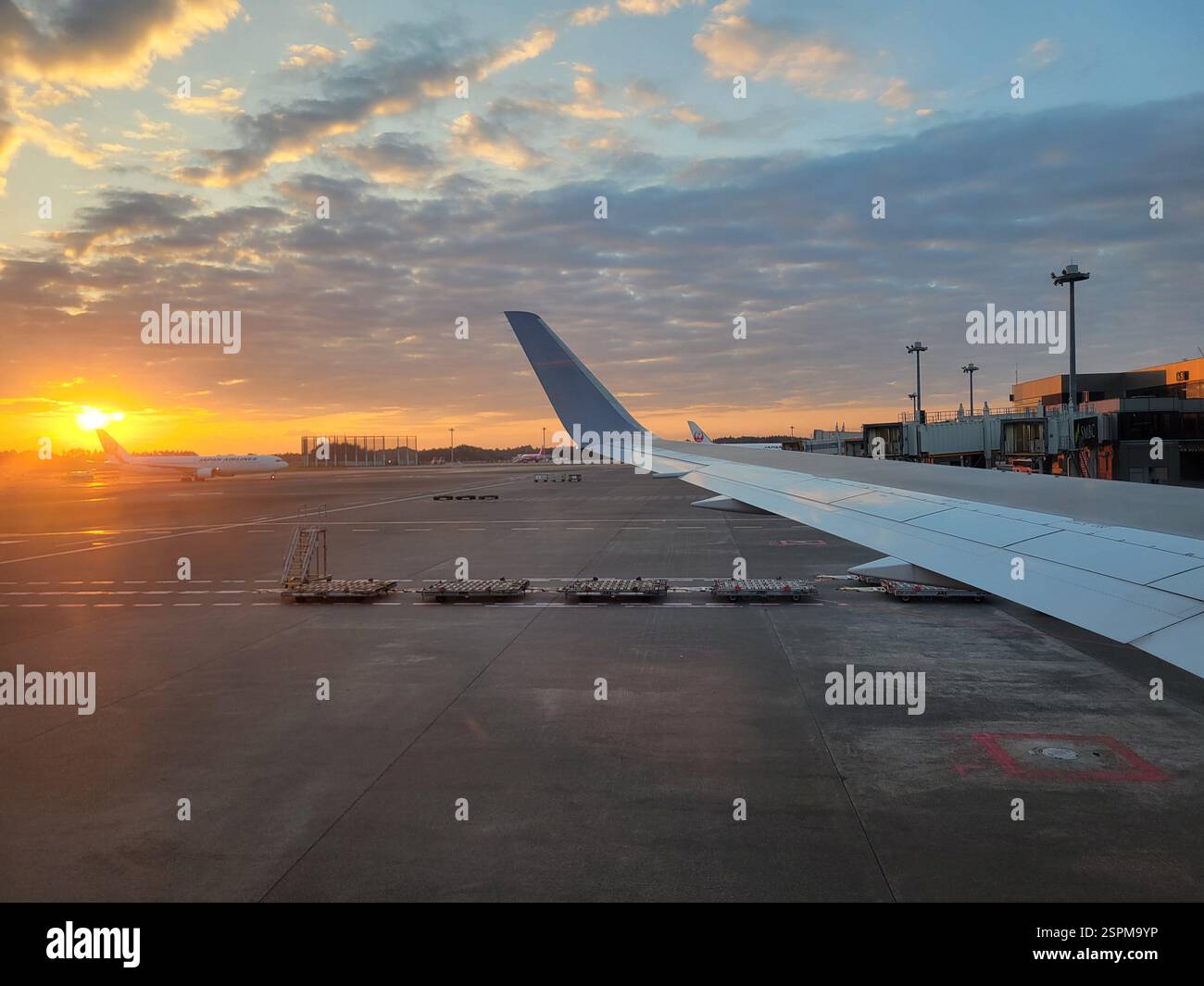 An airplane wing is on an airport runway at sunset Stock Photo - Alamy