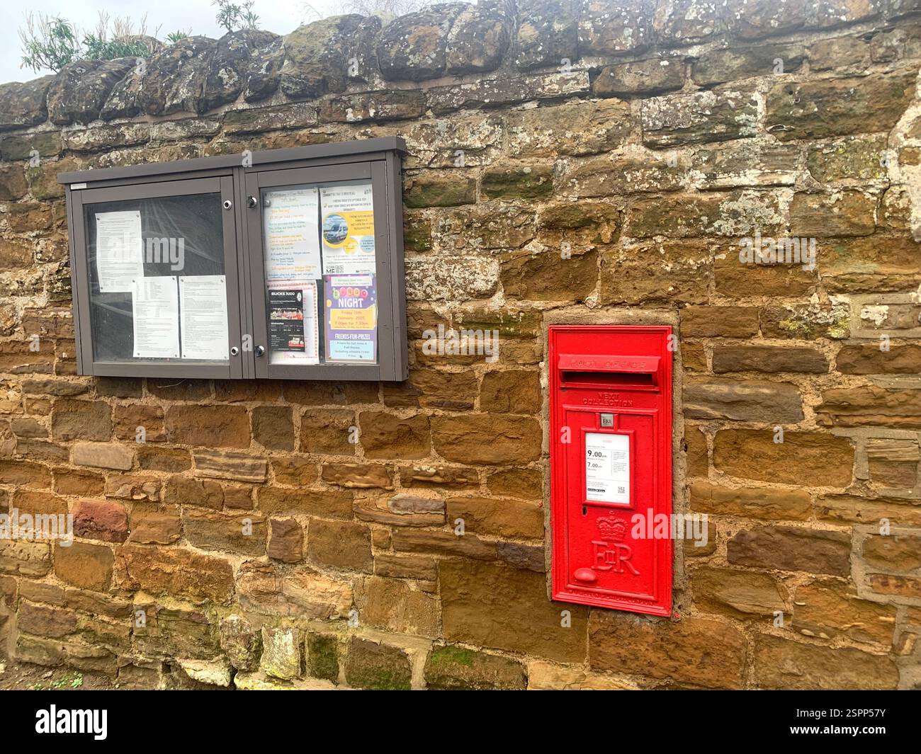 Kislingbury Northamptonshire England Britain UK notice board post box red  stone wall sleepy village cemented cement sign postman cold weather Winter - Smartphone Captured Stock Image