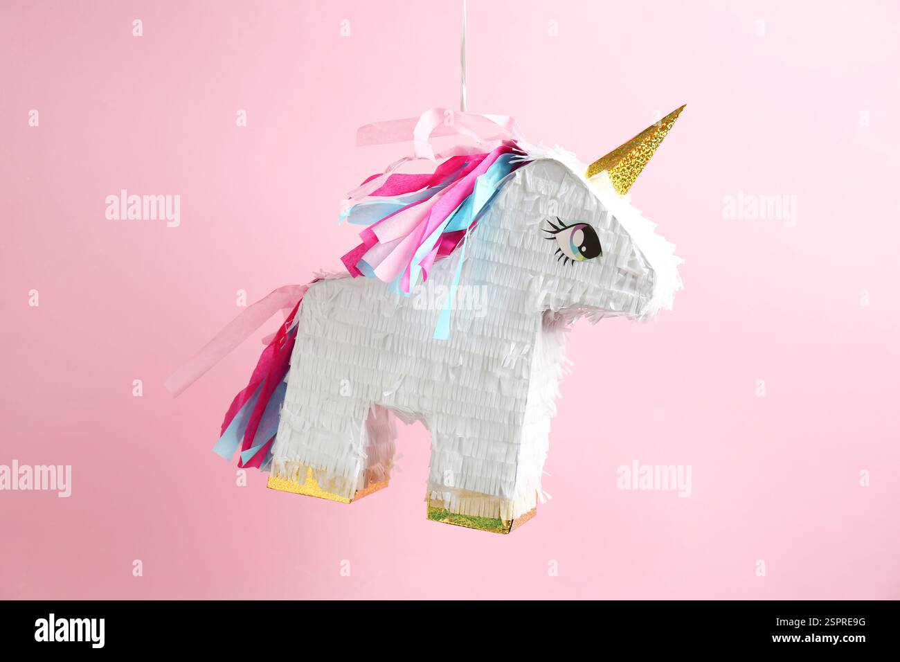 Bright pinata in shape of unicorn hanging on pink background Stock ...